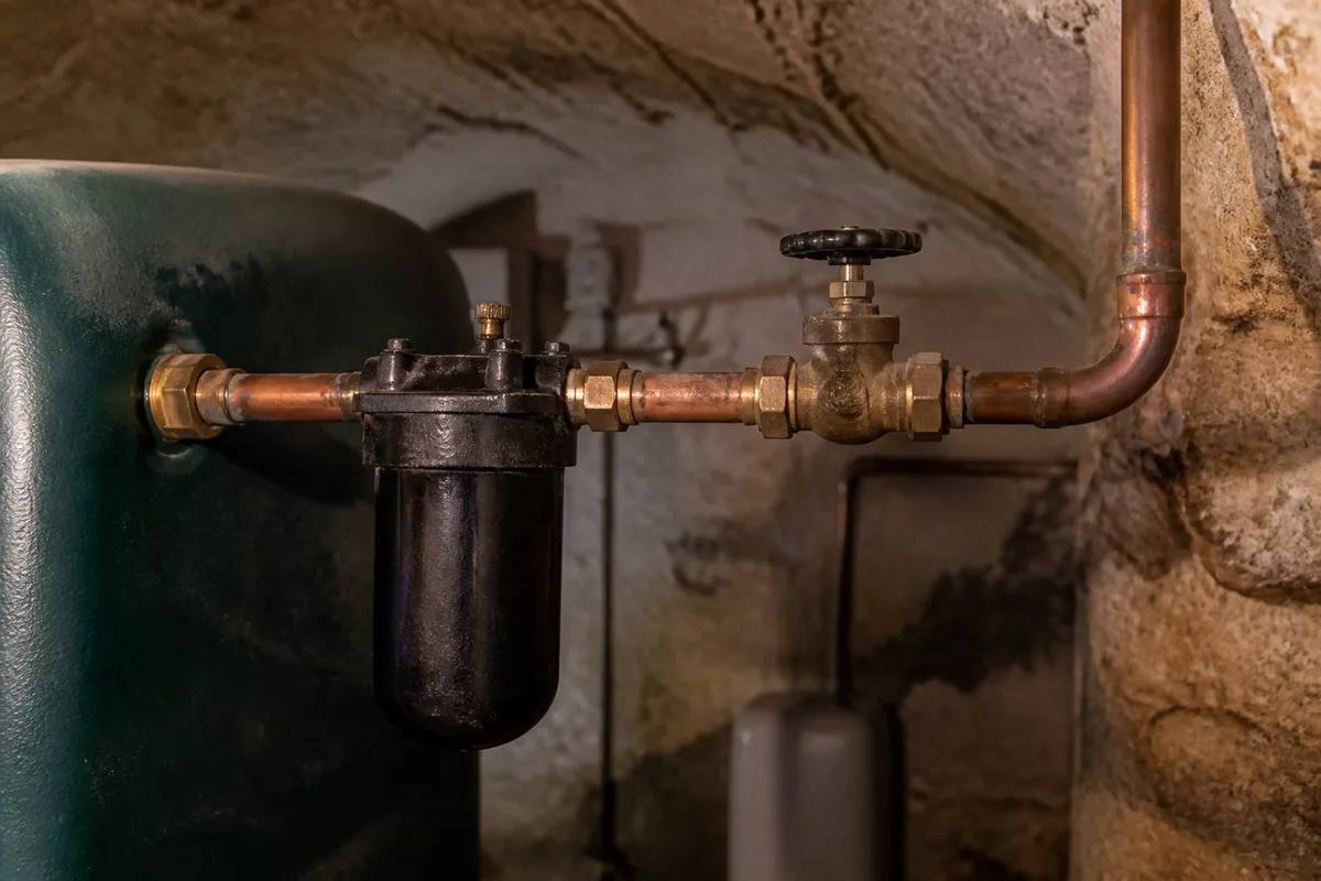 Cuve à fioul métallique installée dans une cave de maison ancienne avec son filtre